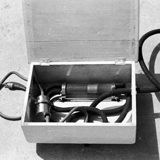 Open box contains equipment, possibly scientific or industrial in nature.