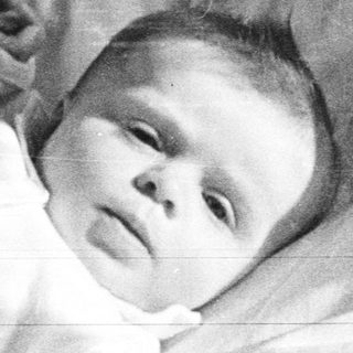 Here's a brief summary of the image: Baby in a basket, wrapped in white fabric.
