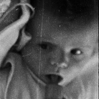 Black and white image of a baby being held.