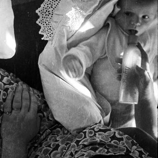 Black and white image of a baby being held.