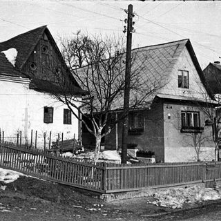 Here's a brief summary of the image: Snow-covered homes with wooden fences and utility poles.