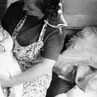 Woman holding baby, vintage photograph with textured background.
