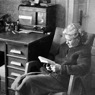 Woman reading in a chair next to a desk.