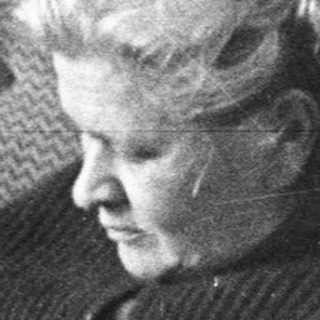 Woman reading in a chair next to a desk.