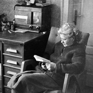 Woman reading in a chair next to a desk.