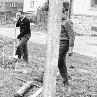 Men working on a fence in a grassy area.