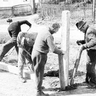 Men installing a monument on a street with onlookers.