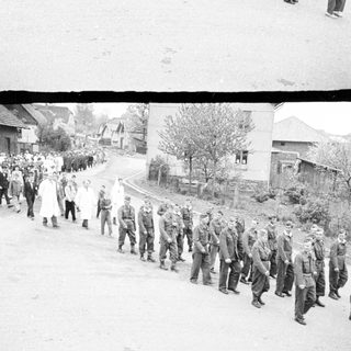 Here's a brief summary of the image: Marching procession of medical personnel and soldiers.
