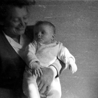 A person holding a baby in a monochrome photograph.
