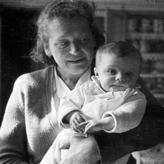 A person holds a baby in a black and white photo.