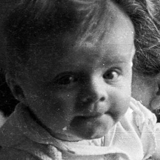 Black and white photo of a baby with curly hair.