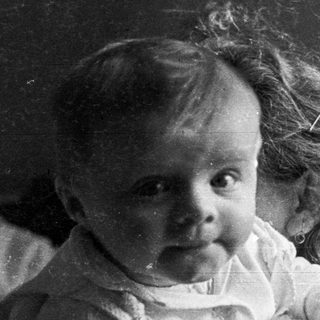 Black and white photo of a baby with curly hair.