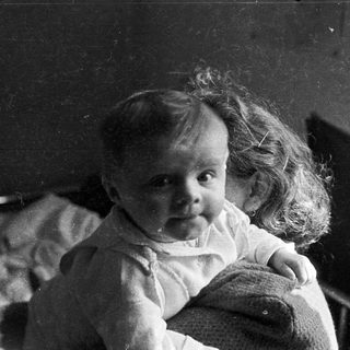 Black and white photo of a baby with curly hair.