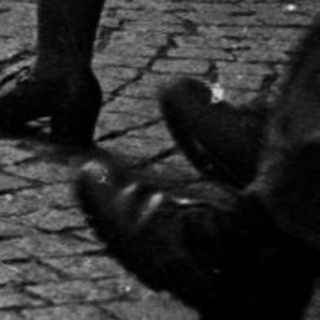 Group of people march down a cobbled street.