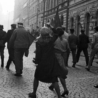 Group of people march down a cobbled street.