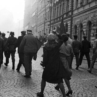 Group of people march down a cobbled street.