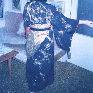 Person wearing a blue kimono stands near a window.