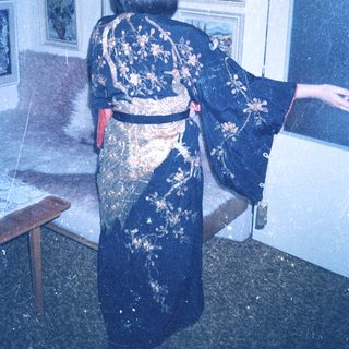 Person wearing a blue kimono stands near a window.
