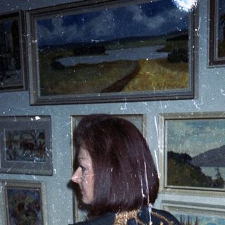 Woman in robe stands in room with artwork.