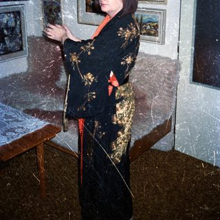 Woman in kimono stands in a room with artwork.