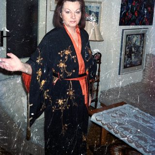 Woman in a kimono stands in a room with art.