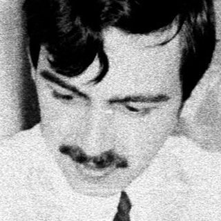 Man with mustache types on a vintage typewriter.