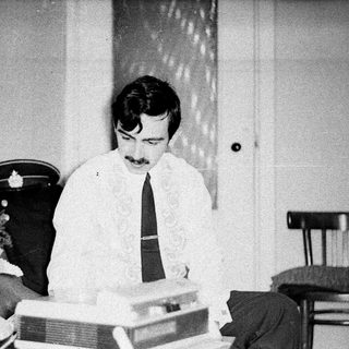 Man with mustache types on a vintage typewriter.