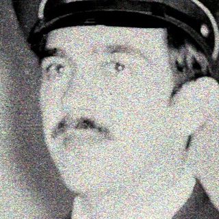 Man in military uniform and peaked cap is pictured.