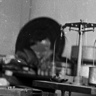 Woman in lab coat smiles behind a workbench.
