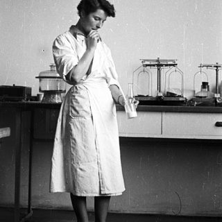 Woman in lab coat holds flask in a laboratory.