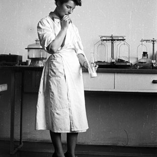 Woman in lab coat holds flask in a laboratory.