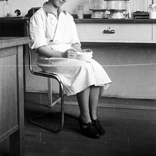 Woman in lab coat sits in a laboratory setting.