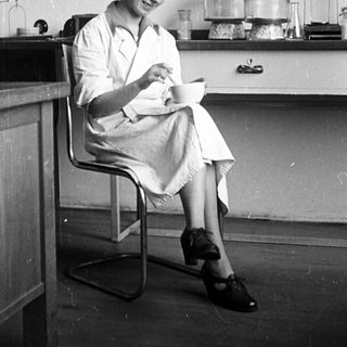 Woman seated in lab, examining something with a smile.