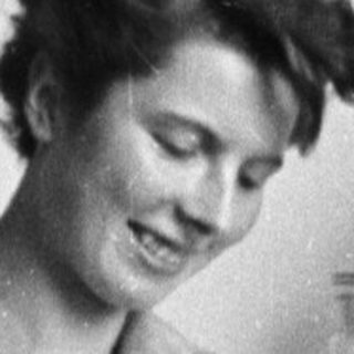 Woman seated in lab, examining something with a smile.