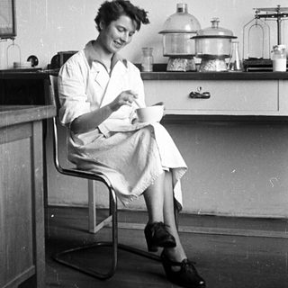 Woman seated in lab, examining something with a smile.