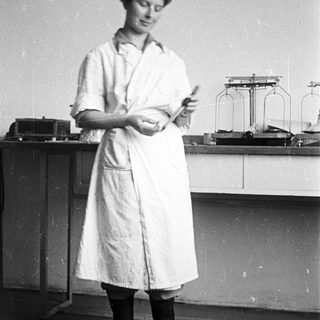 Woman in lab coat examining something in a lab.