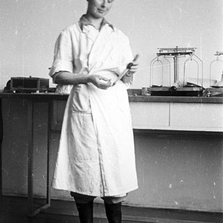 Woman in lab coat examining something in a lab.