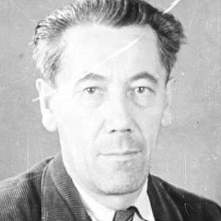 Man in a suit seated near a door.