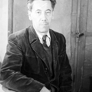 Man in a suit seated near a door.