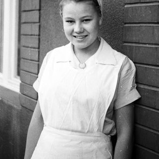 Young woman in a nurse's uniform smiles for a portrait.