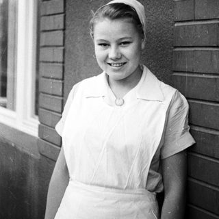 Young woman in a nurse's uniform smiles for a portrait.