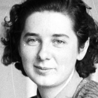 Woman smiles at camera while seated at a desk.