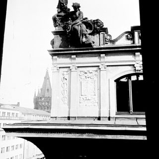 Here's a brief summary of the image: Monumental statue atop a building, viewed from below.