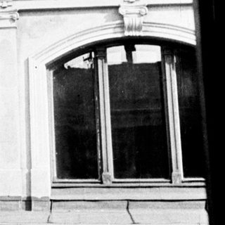 Black and white photo of building with statue and ornate details.