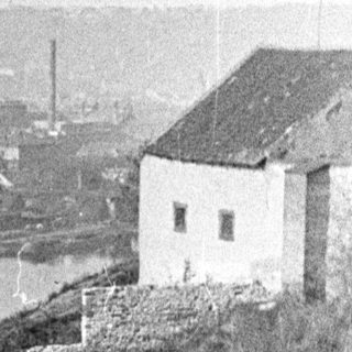 A building overlooks a river with a stone wall.
