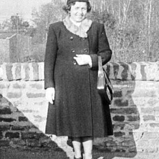 Woman stands on a wall, overlooking a landscape.