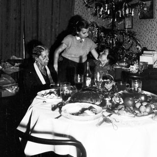 Family gathered around a table, decorated for Christmas.