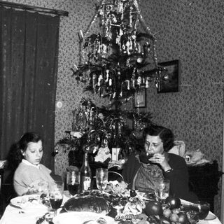 Family seated at a table with a Christmas tree.