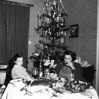 Family seated at a table with a Christmas tree.