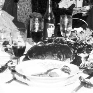 Family seated at a table with a Christmas tree.